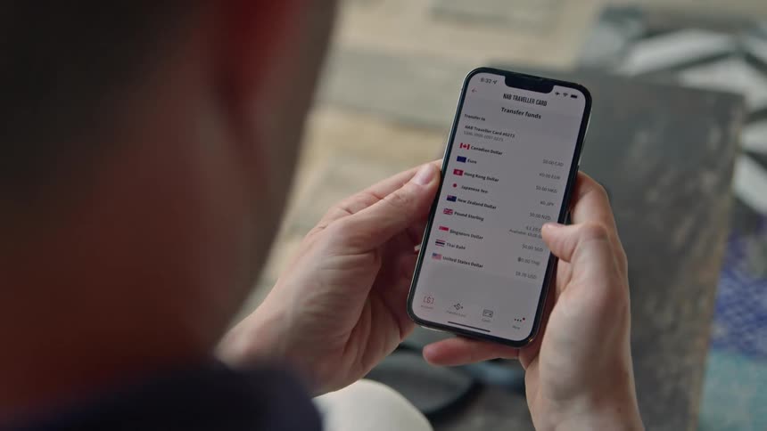 A man is holding his cell phone and using his thumb to scroll through his list