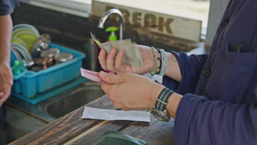 A customer counts out cash for the tab and hands it to the bartender