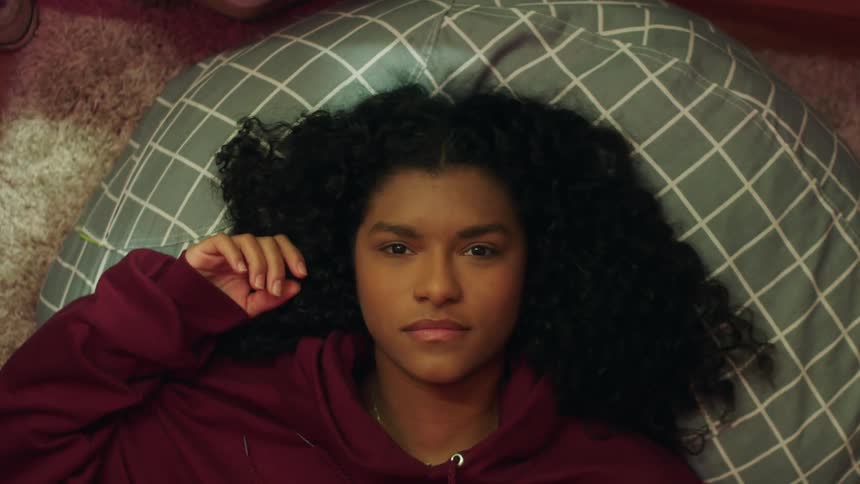 A teenager lies on a beanbag on the floor