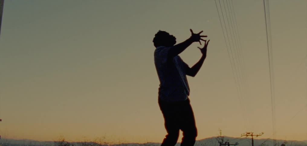 Man stands outdoors silhouetted against red sky