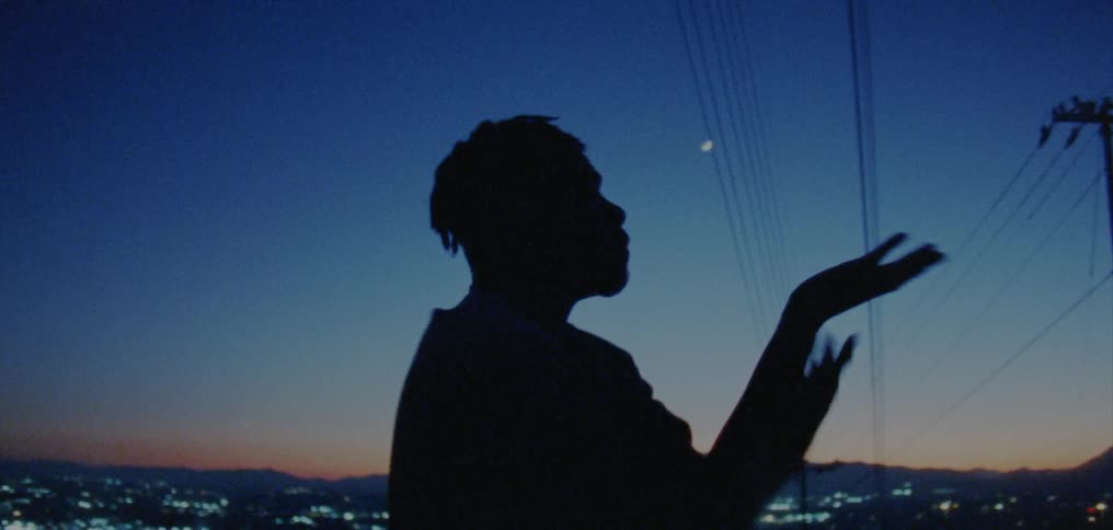 Male dancer dances silhouetted against city and horizon after dusk