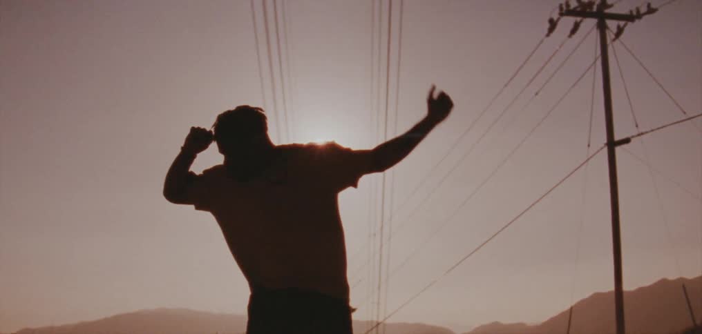 Silhouette of a young man dancing on the countryside at evening