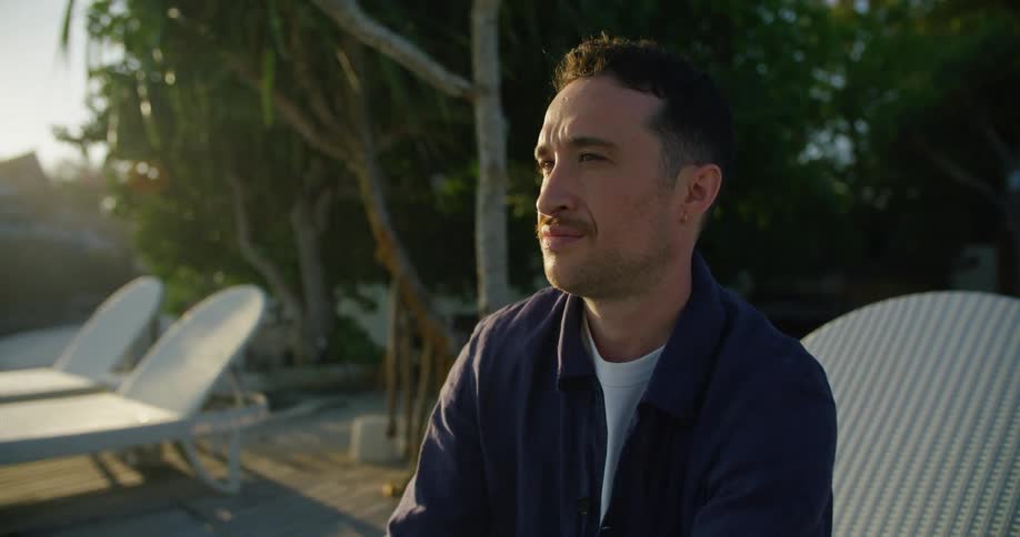 Young man relaxing on a chair on a tropical resort at sunset