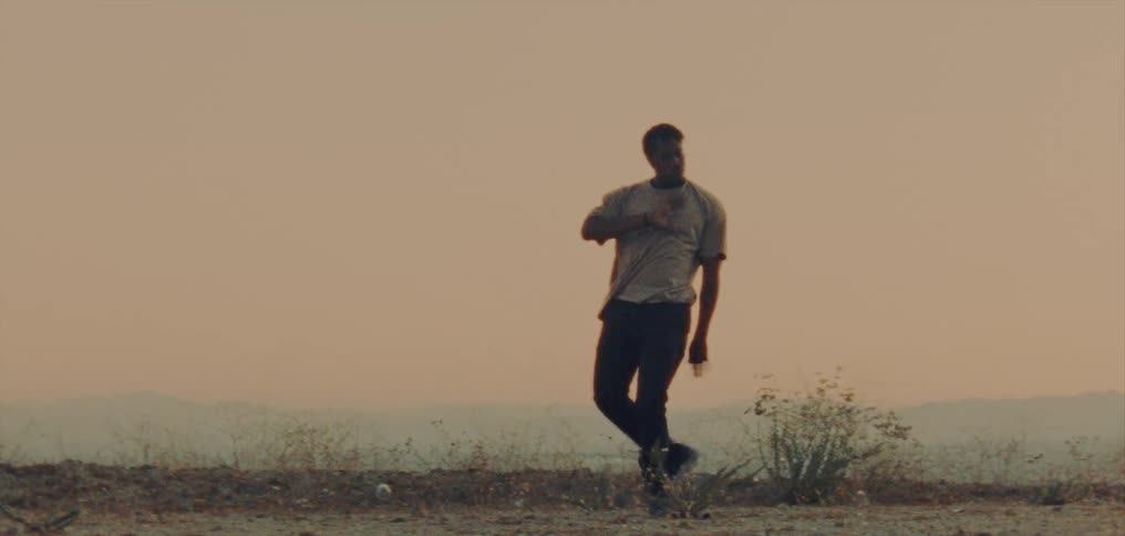 Male dancer performs routine outdoors with fog covered mountains in the background