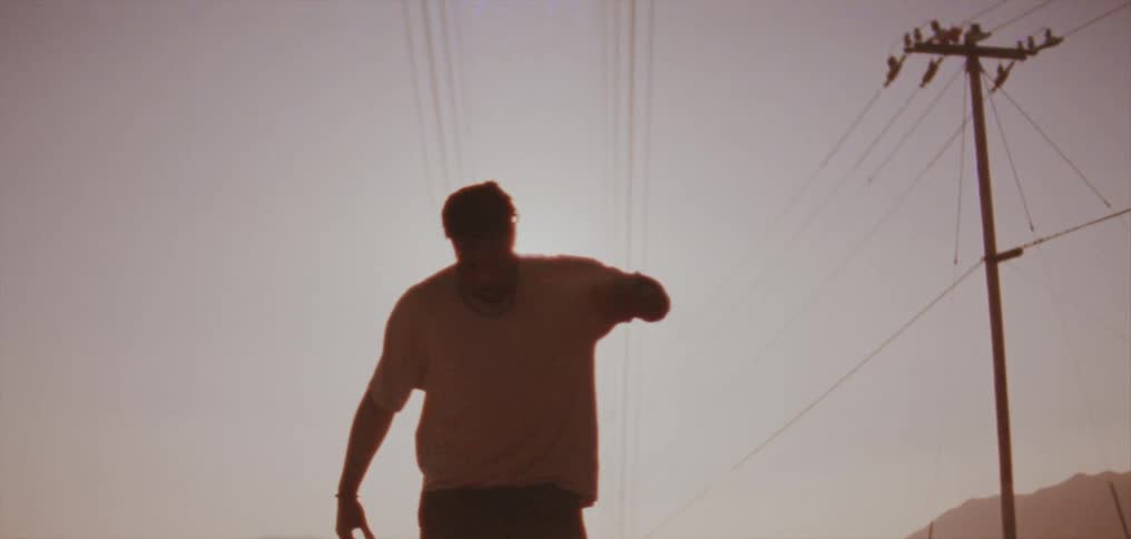 The silhouette of a young man dancing outside in the bright sun