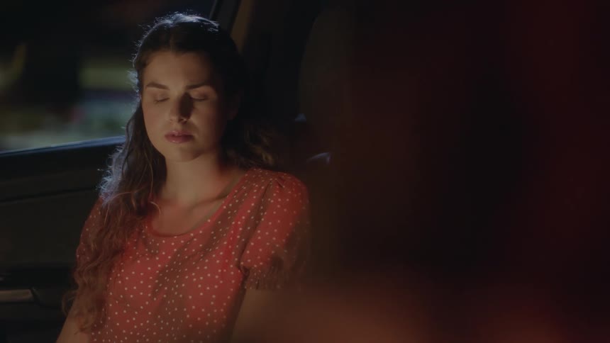 A teenage girl is sitting in an automobile and giving the person next to her a dirty look