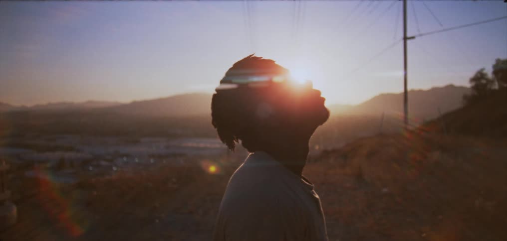 Side profile of man with dreadlocks and white shirt looking up at the sky against the sky