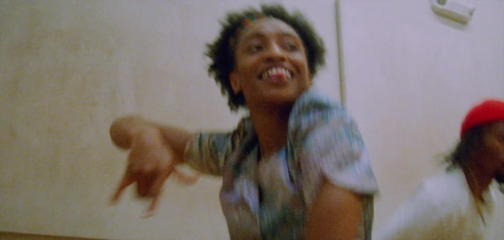 A group of people laugh while doing a choreographed hip hop style dance in a gym