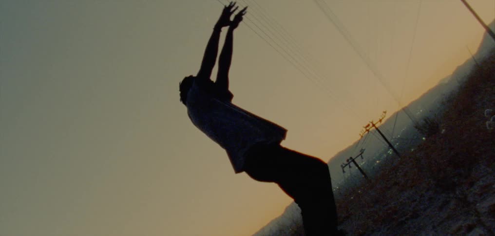 The silhouette of a man dancing against a golden sky