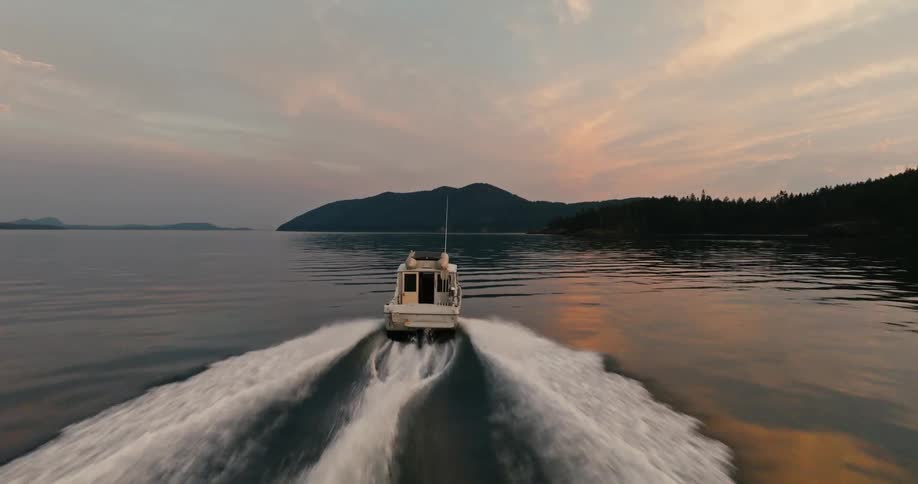 A motor boat with a cabin leaves a wake as it travel across the water toward land