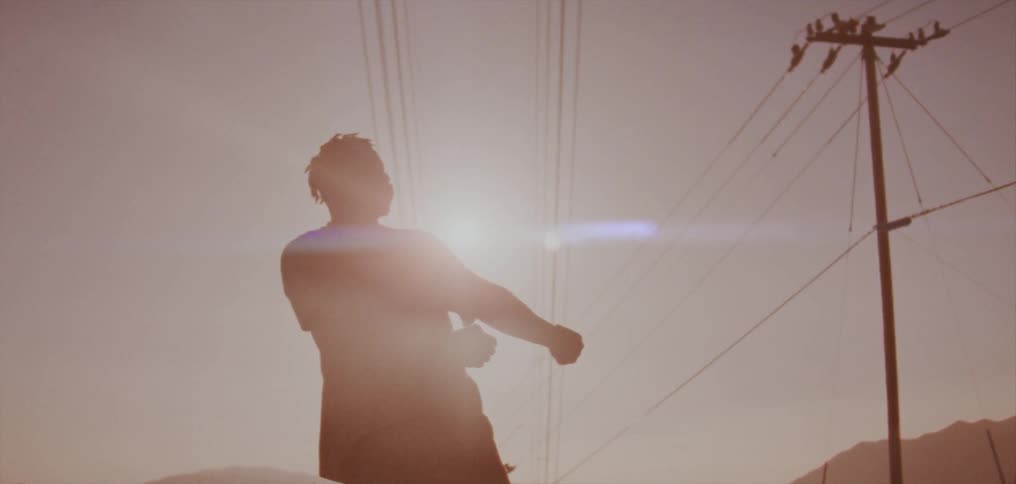 A man dances next to power lines as the sun shines down on him