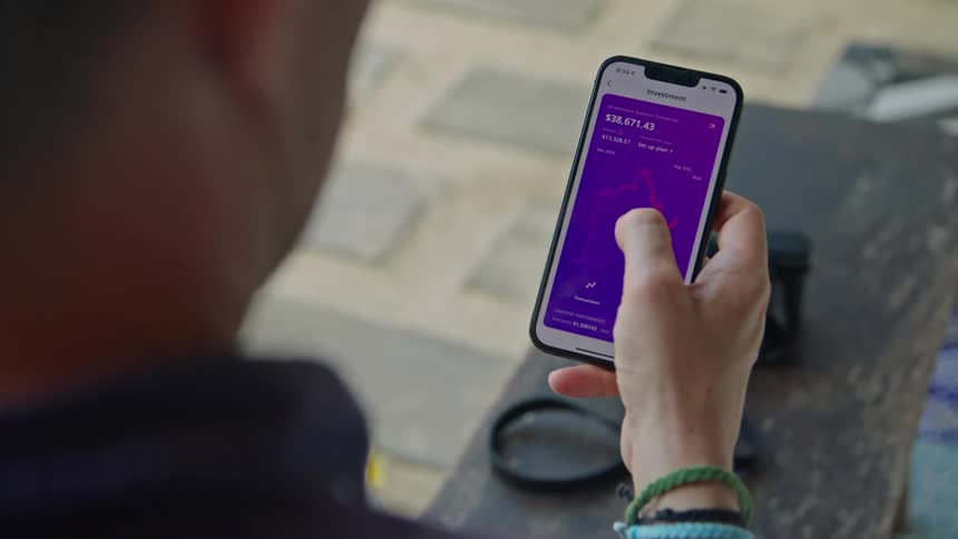 Man unlocks phone with his face and then looks over financial graphs