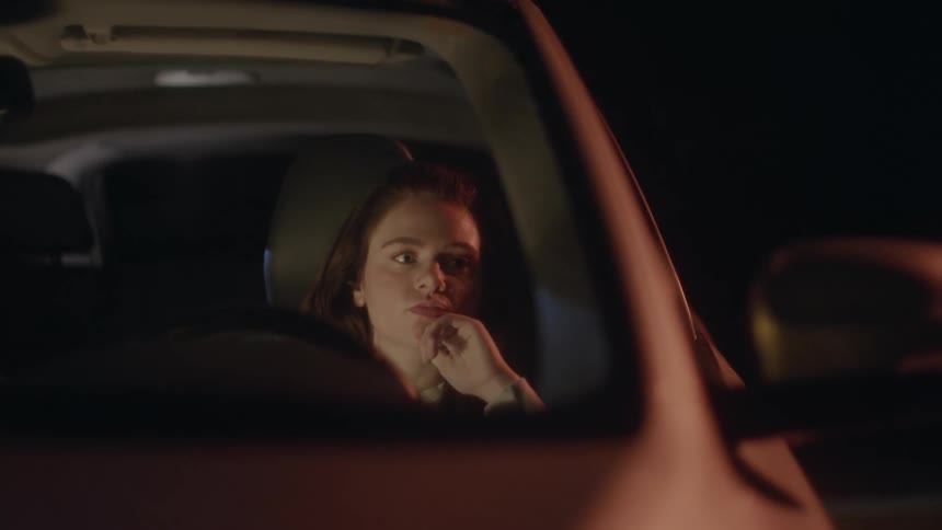 A woman is sitting in and automobile and she closes her eyes