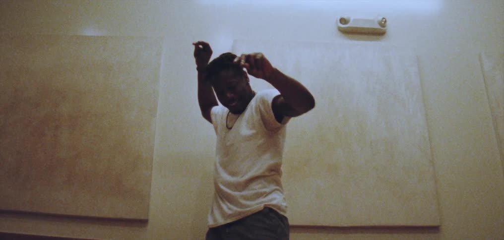 Young happy man wearing a white shirt dances alone energetically on a room