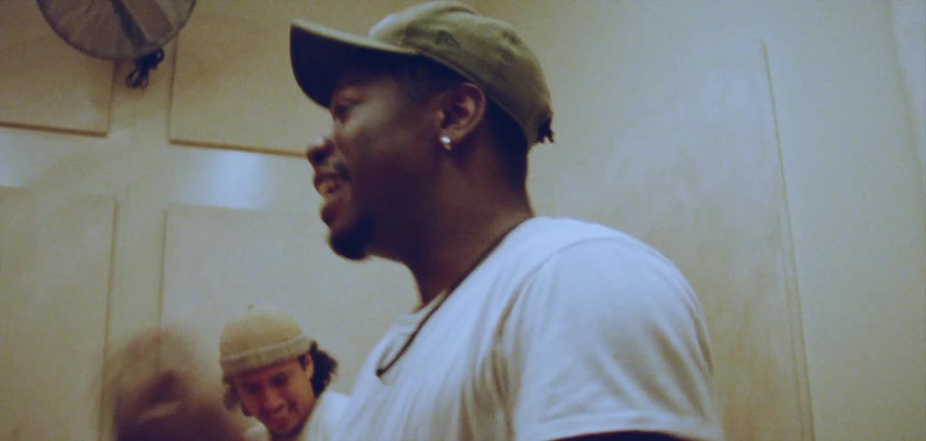 A young man smiling as he dances with friends in a studio