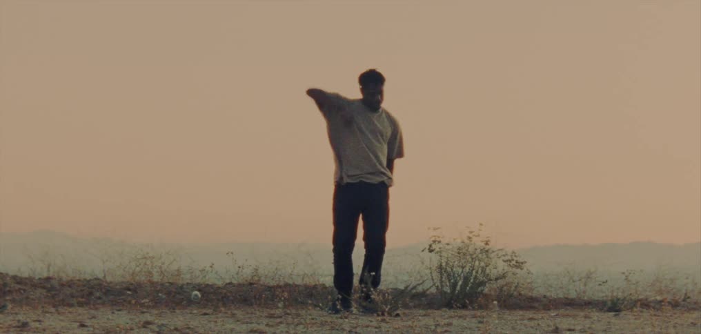 A man dances outdoors in a field on a foggy day