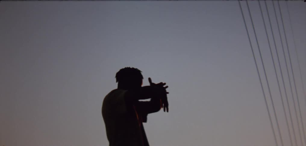 Silhouette of a young man dancing on the countryside at evening