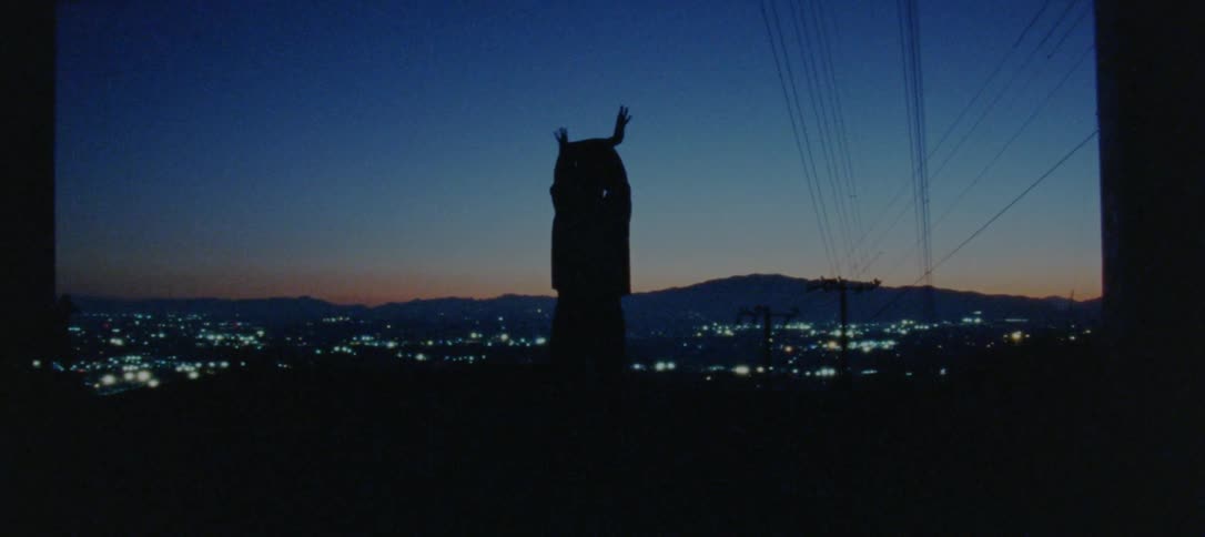 The silhouette of a man dancing and moving his arms and hands above his head on a hill