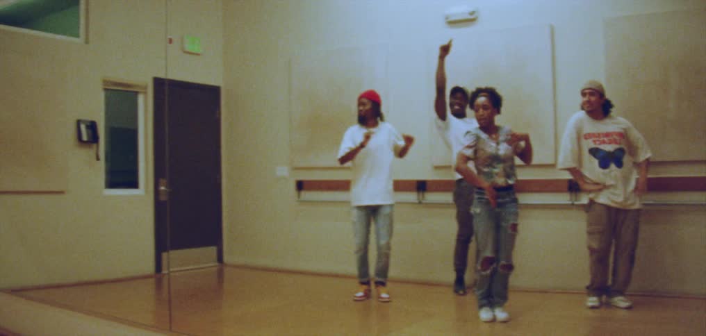 Group of happy people performing a choreographed dance in front of a mirror on a studio