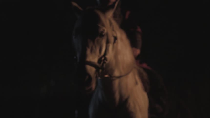 A man riding a horse outside at night