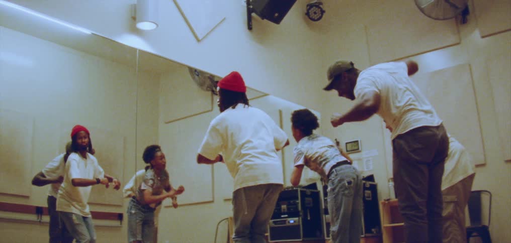 Group of happy people performing a choreographed dance in front of a mirror on a studio