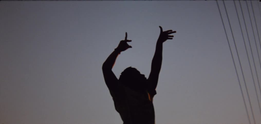 Silhouette of a young man dancing on the countryside at evening
