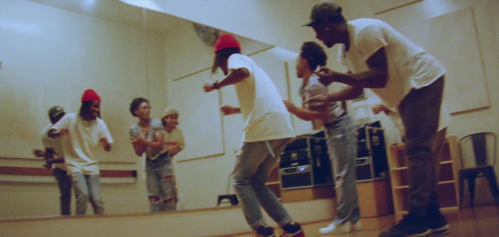 Group of happy people performing a choreographed dance in front of a mirror on a studio