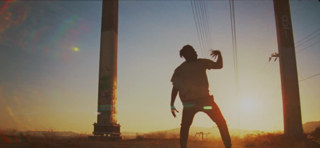 A man performs a hip hop style dance in a field