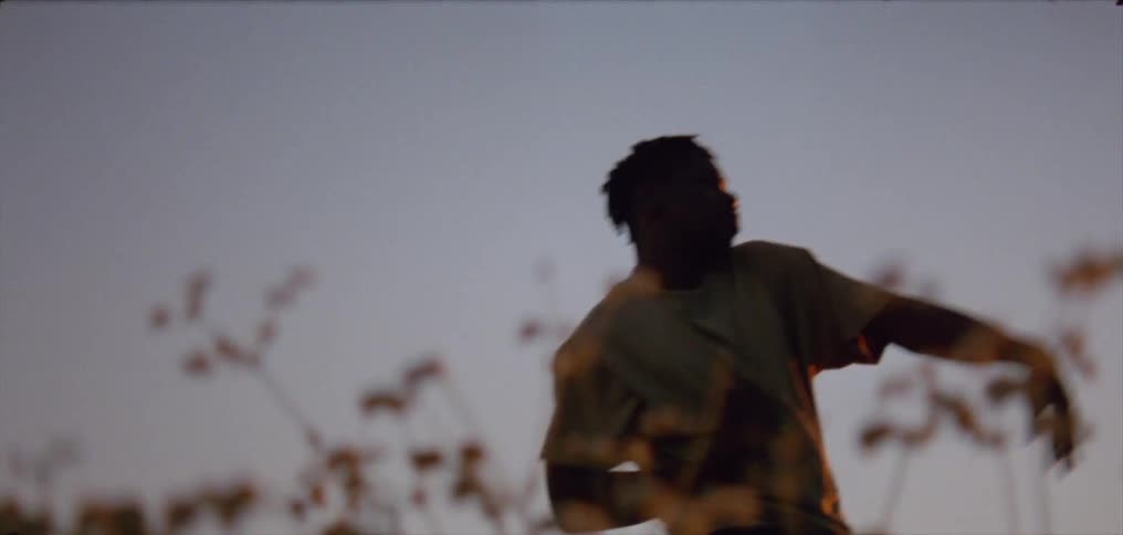 Silhouette of a young man dancing on the countryside at evening