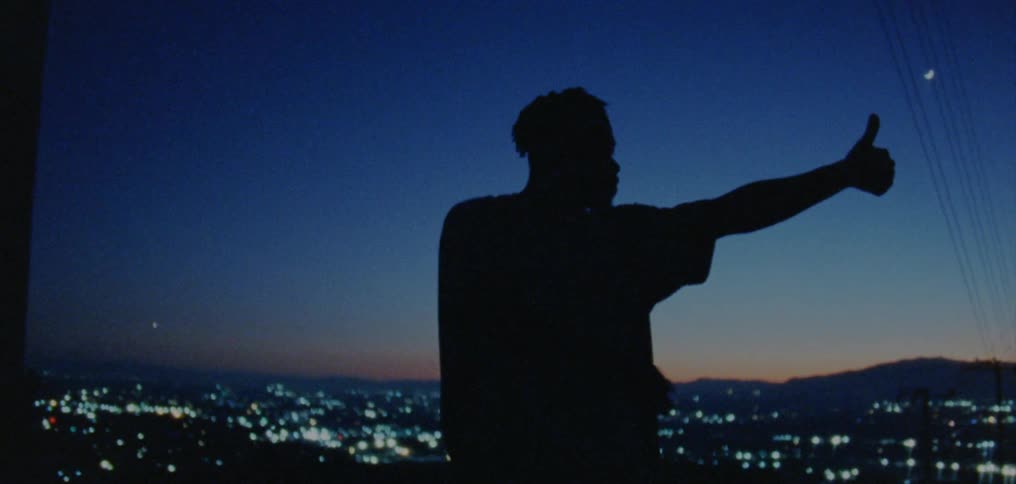 A man dances outside with a vantage point overlooking a neighborhood