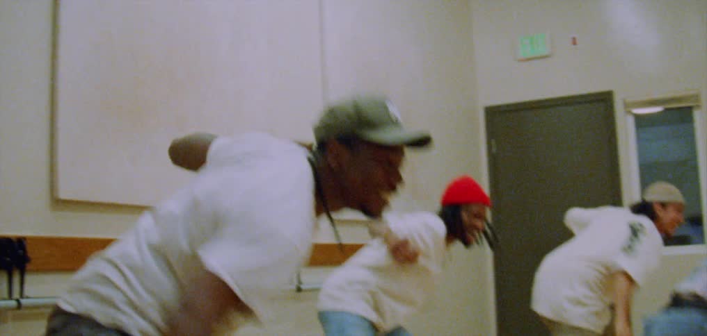 A group of four friends smile and laugh as they dance together in a studio