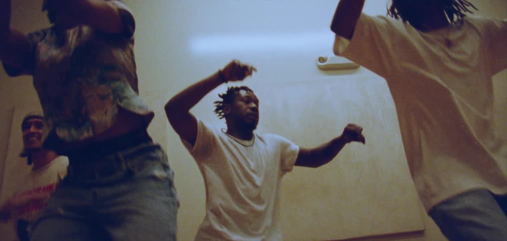 Three men and a woman dance in a studio