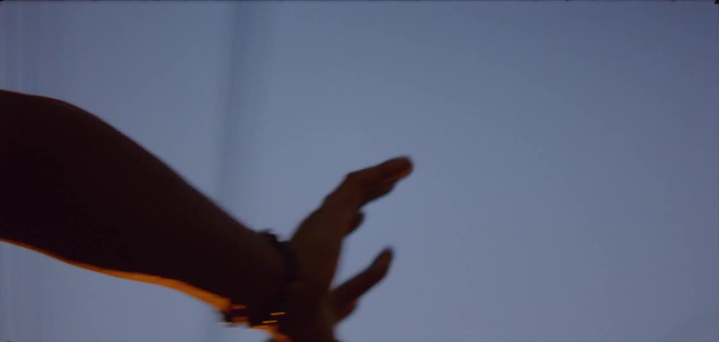 Man waving hands slowly against the blue sky at evening