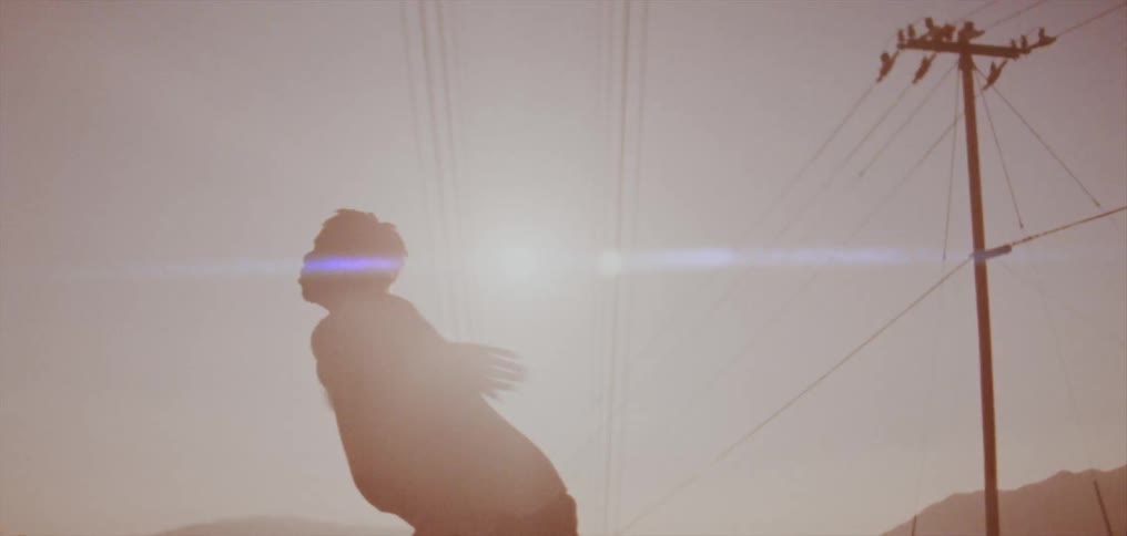 Male dancer with dreadlocks and white shirt dancing is silhouetted against the sky in the country