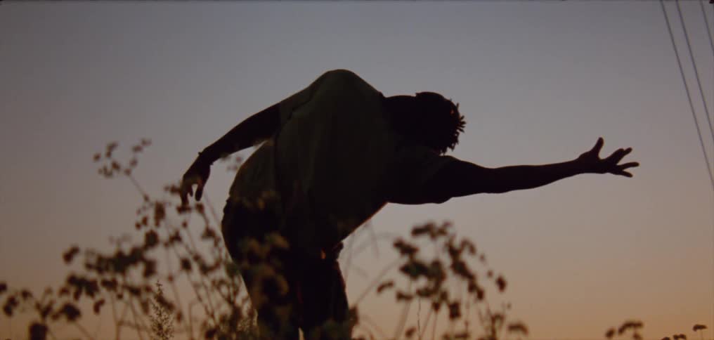 Silhouette of a young man dancing on the countryside at evening