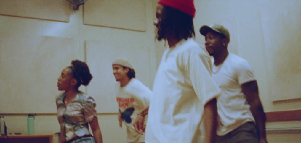 A group of people perform a synchronized dance in a dance studio