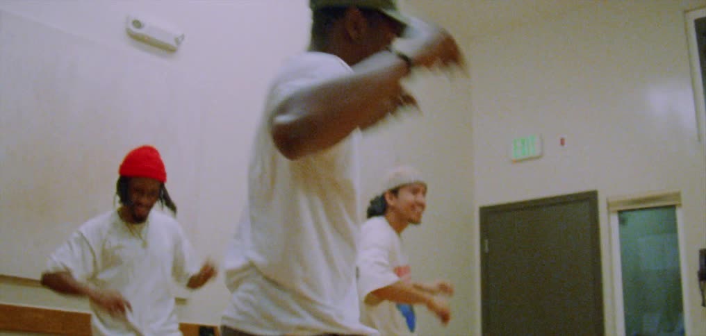 A group of four young people smiling as they dance together in a studio