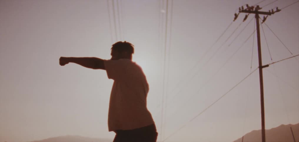 Silhouette of a young man dancing on the countryside at evening