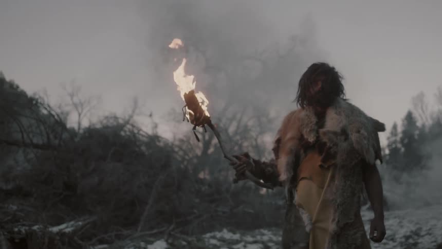 A man dressed in animal hides carrying a torch
