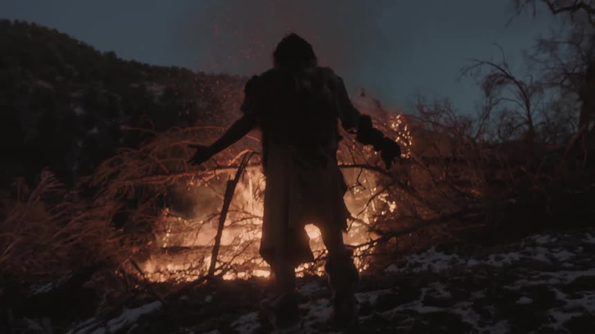 A man raises his arms in front of a fire