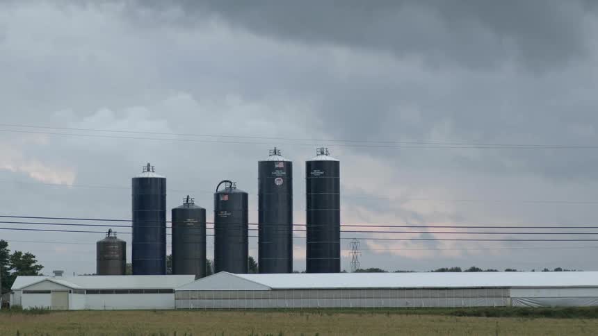 Clouds floating above rural silos and buildings at sunset