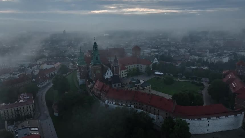 Fog shrouds city near large castle and attached cathedral