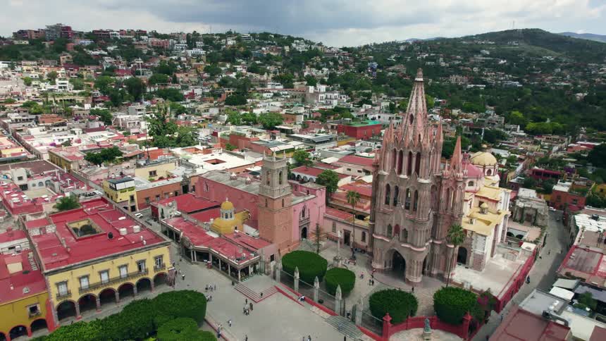 People walk past a church and buildings in a city