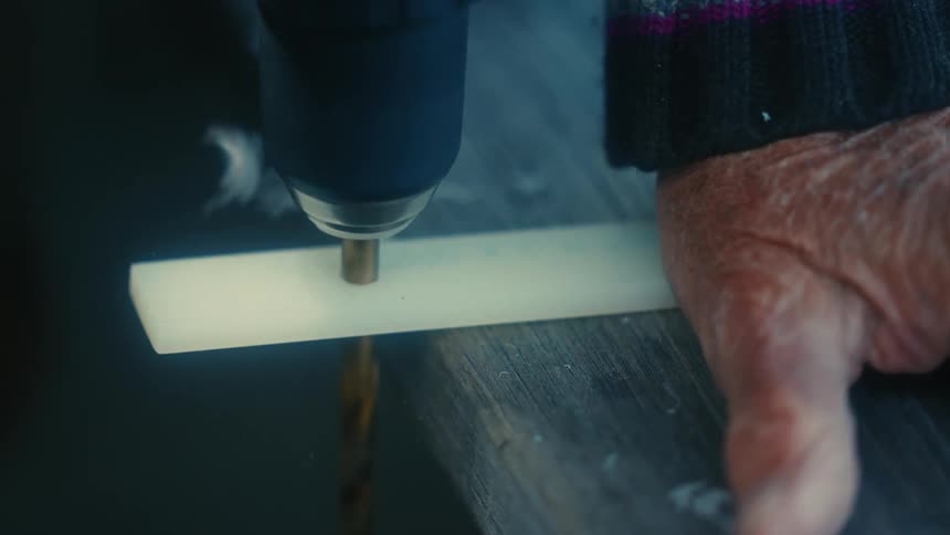 A man drills through a piece of wood
