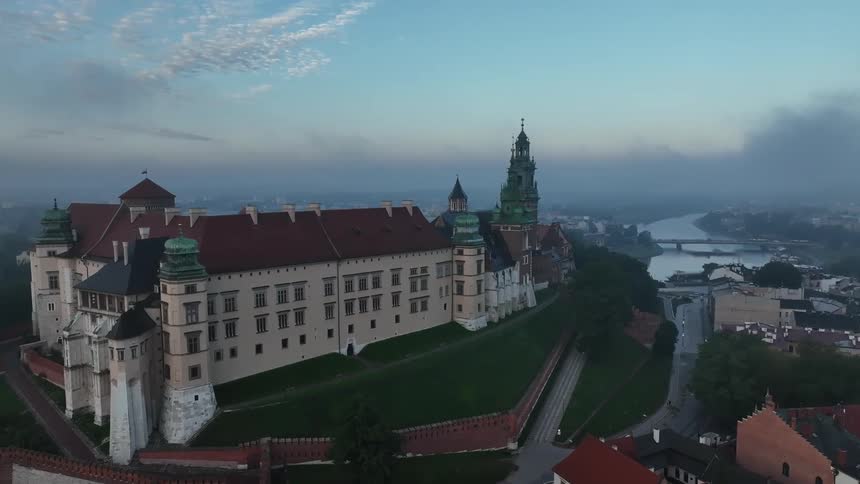 The wawel castle in krakow poland with lush green grounds under a cloudy sky
