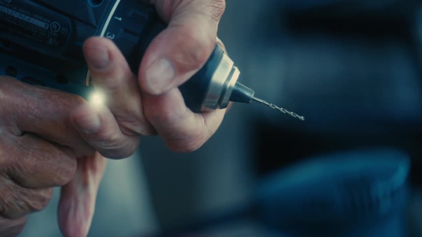 A man holds a drill and turns it on