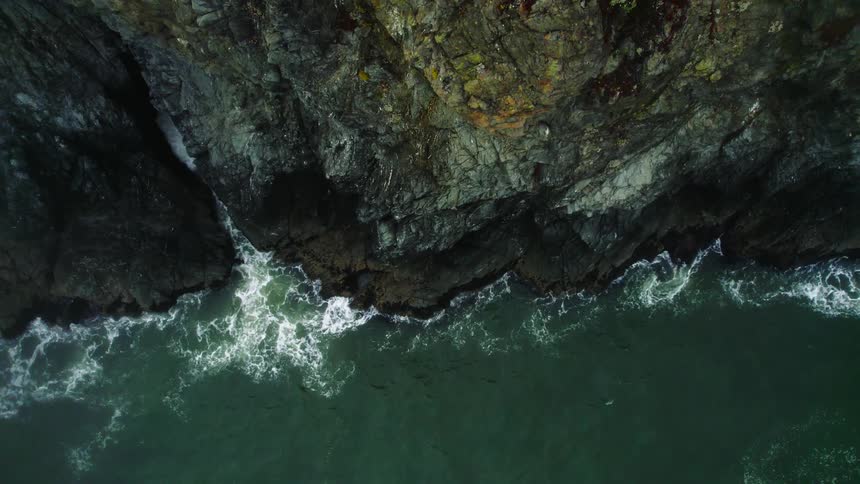 A steep cliff over the ocean during the day