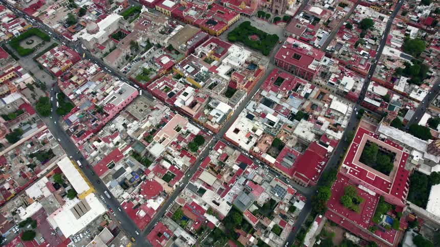 Cars traveling on city streets with colorful buildings and squares