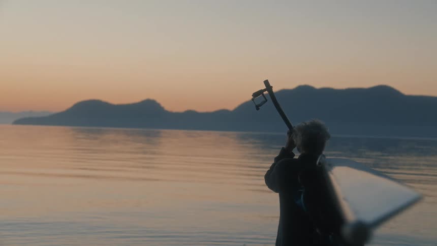 A man carrying a kayak walks towards the water