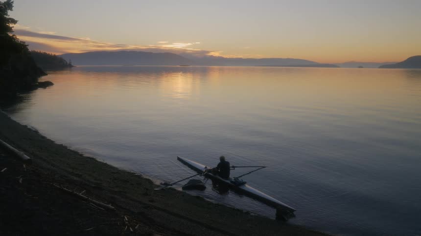 A person sitting in a kayak on a lake at sunset